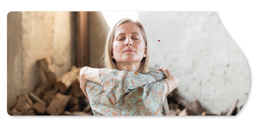Francesca maffioletti, insegnante di yoga, seduta a braccia incrociate con gli occhi chiusi che abbraccia se stessa