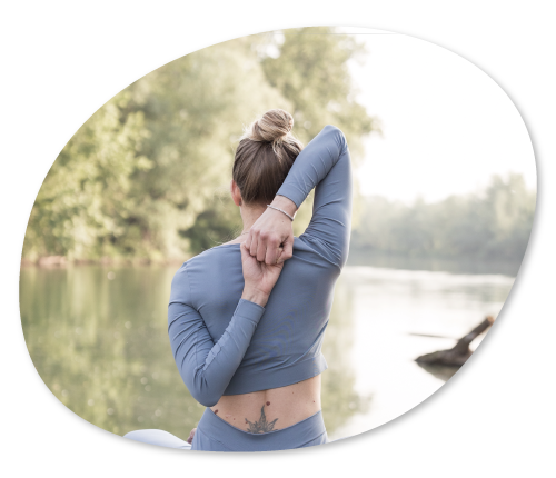 Posizione di yoga con braccia dietro la schiena, davanti ad un lago